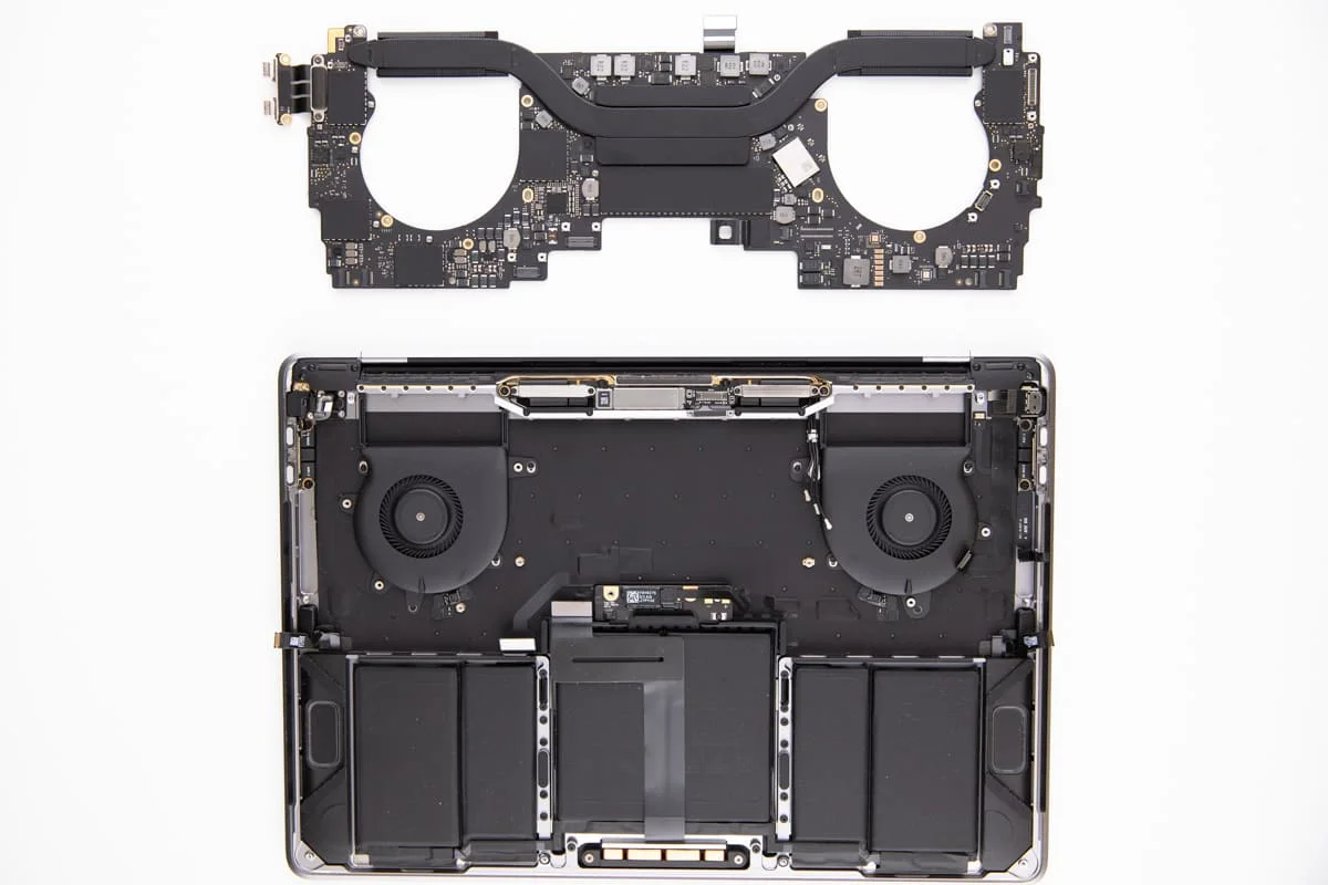 Disassembled view of a laptop showing the internal chassis with cooling fans and battery, and the removed motherboard above.