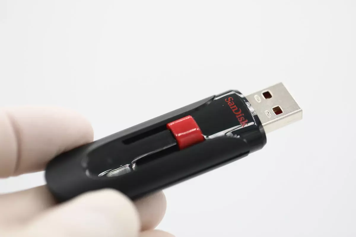 Hand holding a SanDisk USB flash drive with a retractable connector.