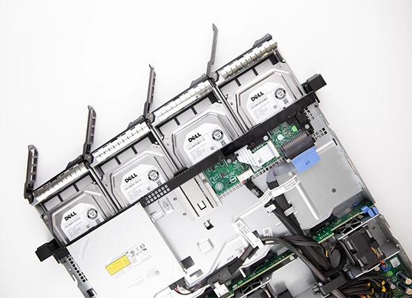 Internal view of a server showing four Dell hard drives installed in hot-swap bays with surrounding components and cabling.